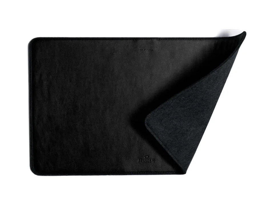 Black Harber London leather desk mat with one corner folded to show the grey felt underside, on a white background