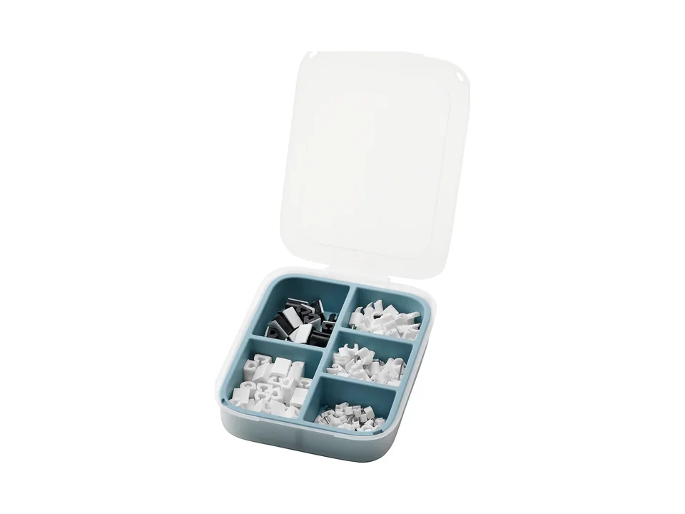 Boîte IKEA TRIXIG ouverte avec des clips pour câbles blancs et noirs rangés dans les compartiments
