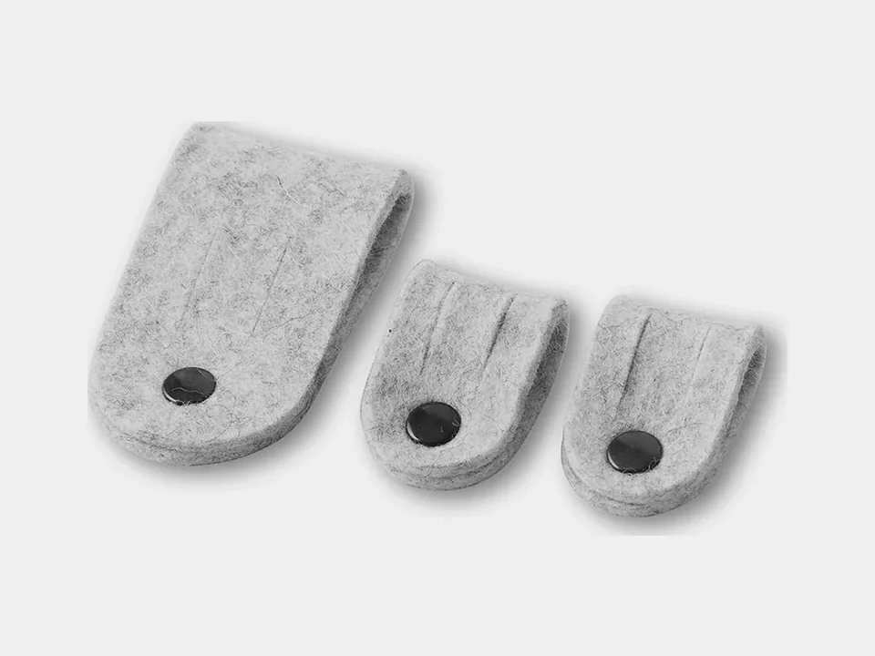Trois attache-câbles Oakywood en feutre gris clair, un grand et deux petits, sur fond gris clair